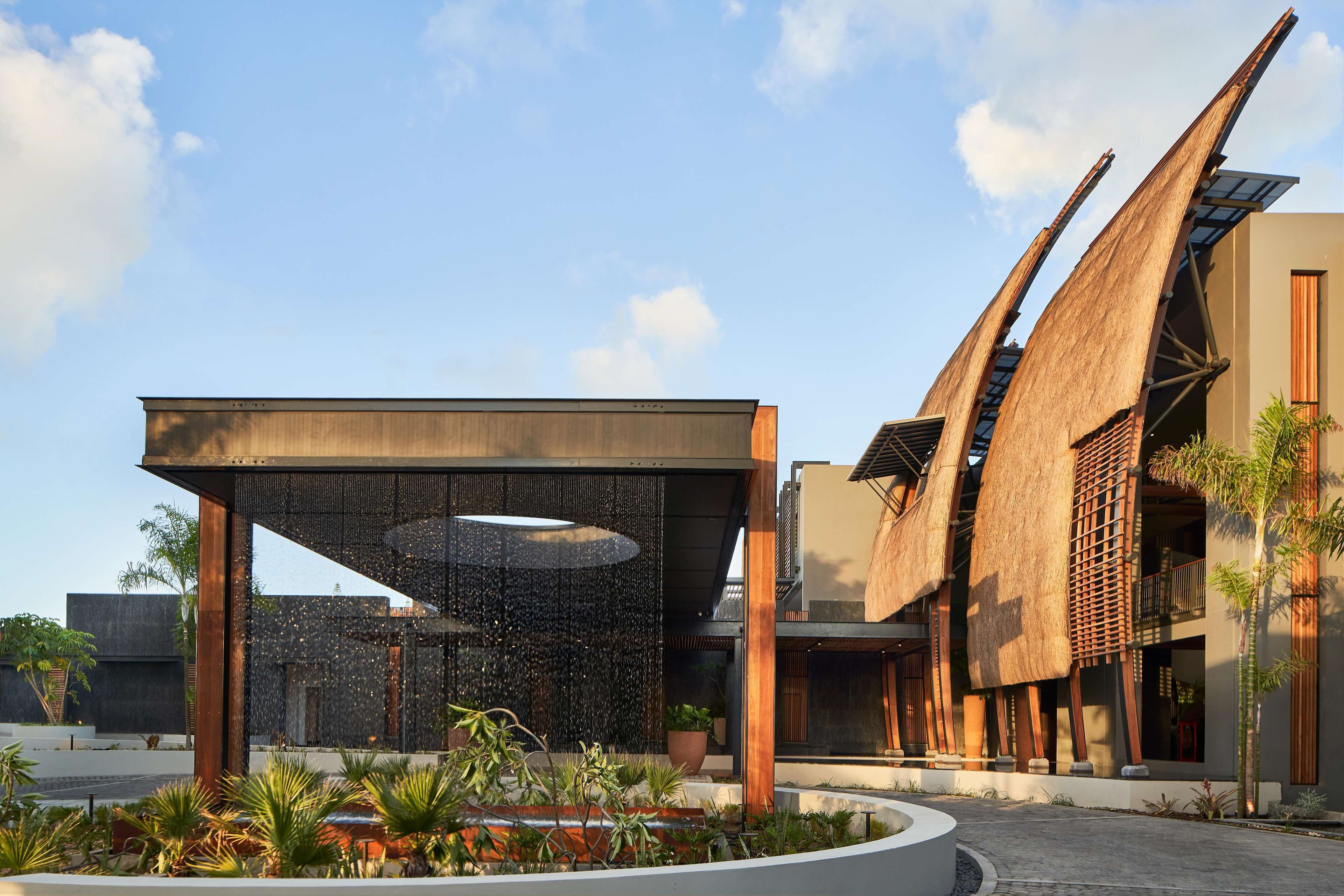 Un edificio moderno con un diseño arquitectónico único, que presenta una fuente central y zonas verdes circundantes.
