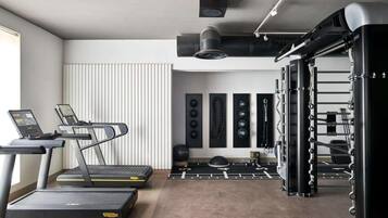 Un gimnasio con cintas de correr, una estructura para sentadillas y varios pesas.