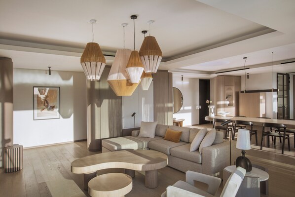 A modern living room with a sectional sofa, a wooden coffee table, and pendant lighting. - LUX* Grand Baie (Grand-Baie)