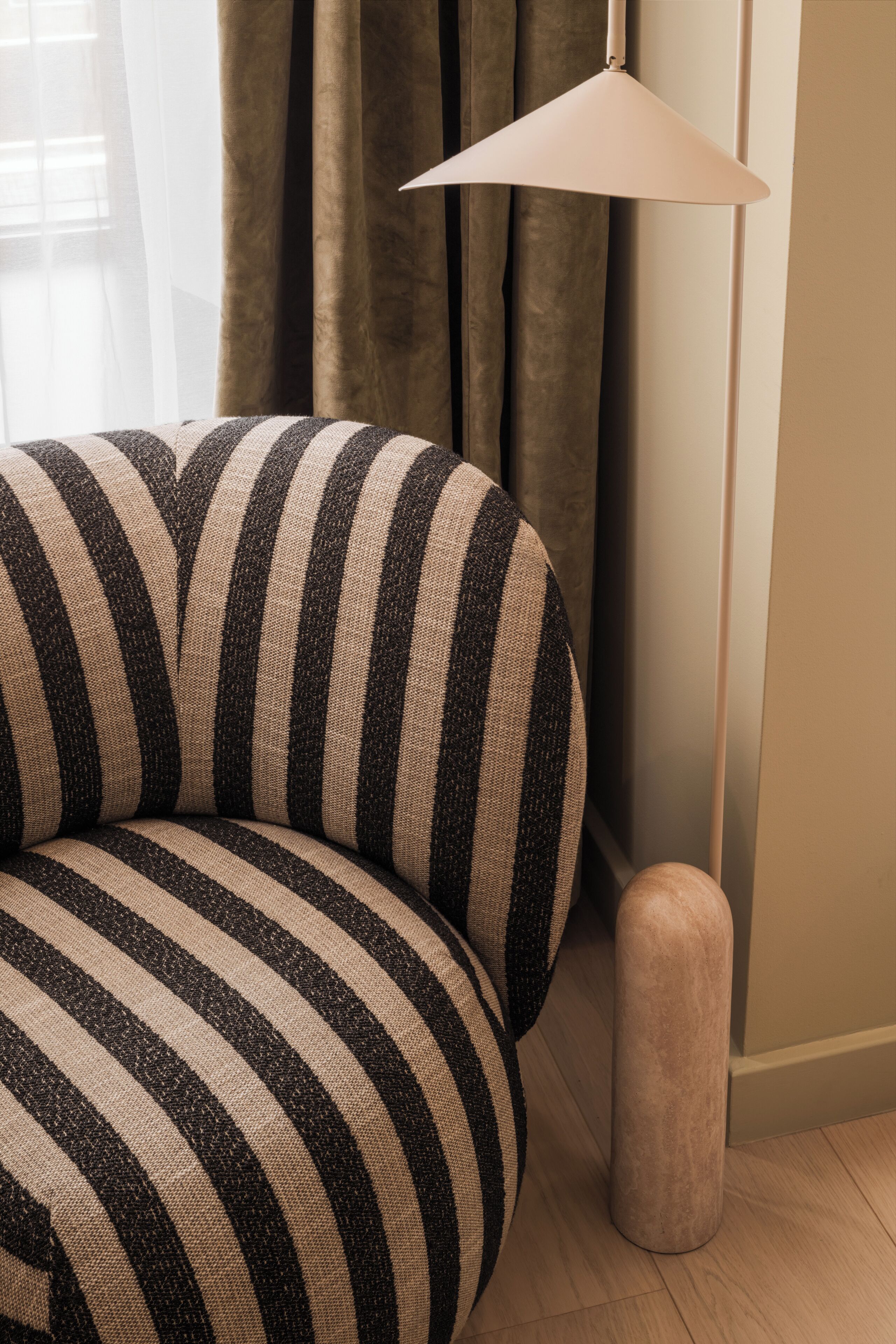 Un sofá a rayas en una habitación con una lámpara y cortinas.