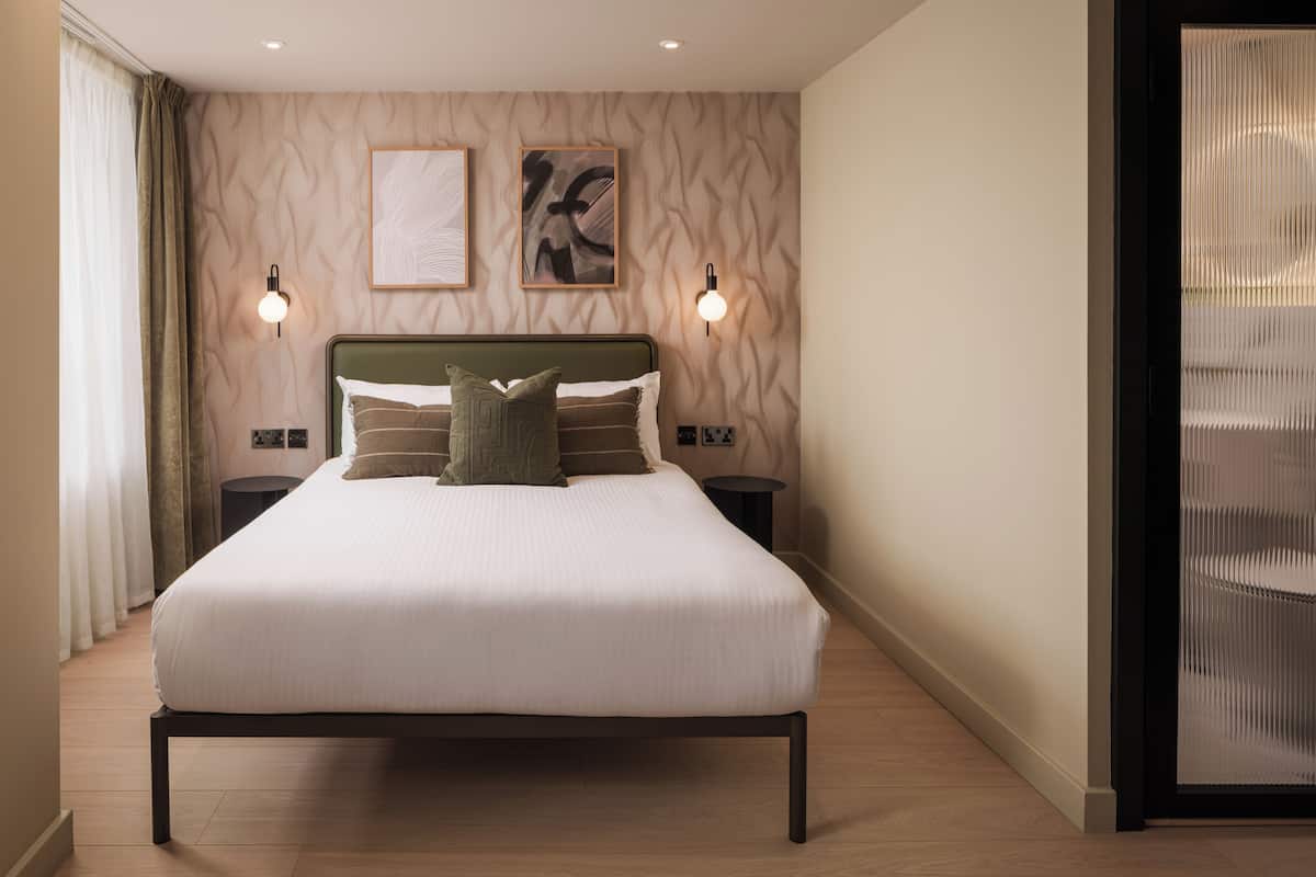 A neatly arranged bedroom with a large bed, two bedside tables, and two wall-mounted lights.