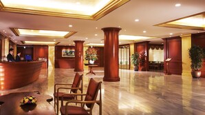 A spacious lobby with a reception desk, several chairs, a large potted plant, and a dining area in the background. - Sejong Hotel (Seoul)
