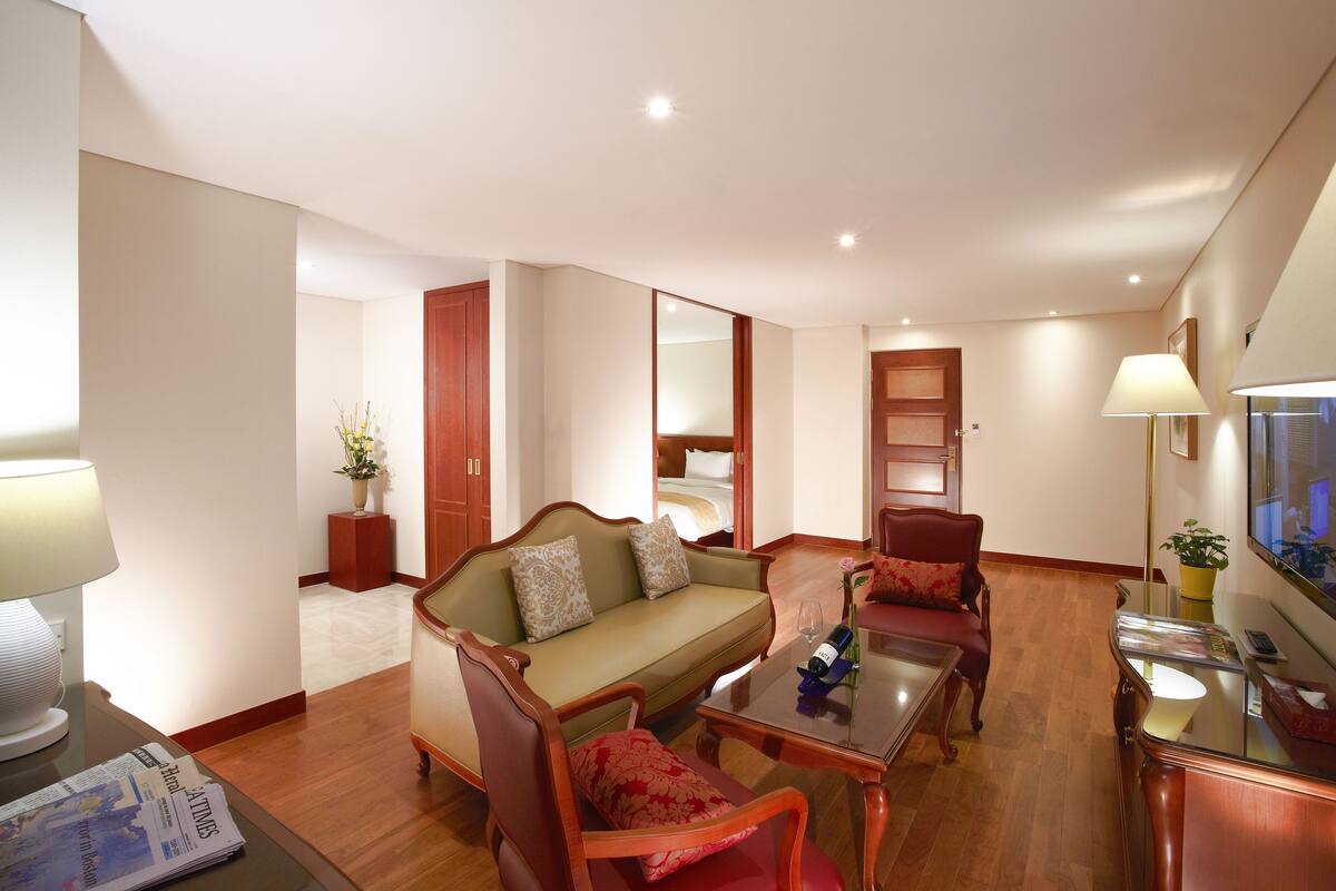 Habitació d'hotel amb sofà, butaques, taula de cafè, televisió i làmpada.