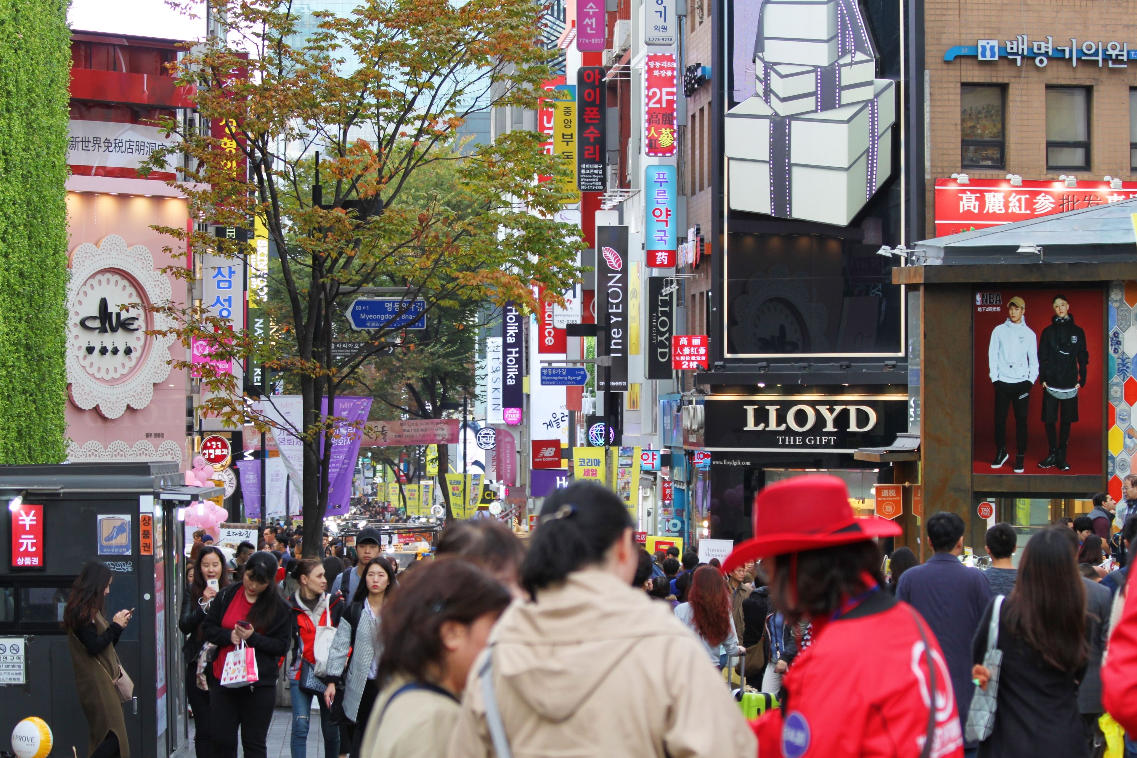 A busy urban street with various shops and advertisements.