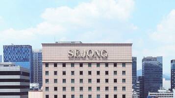 A building with 'SEJONG' prominently displayed on the facade, surrounded by modern high-rise buildings.