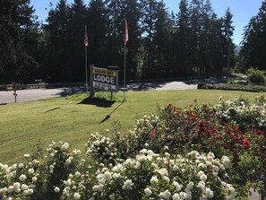 A sign for Sequim Bay Lodge with a grassy area and flowers in the foreground. - Sequim Bay Lodge (Sequim)