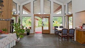 A hotel lobby with a high ceiling, large windows, a reception desk, and a dining area. - Sequim Bay Lodge (Sequim)