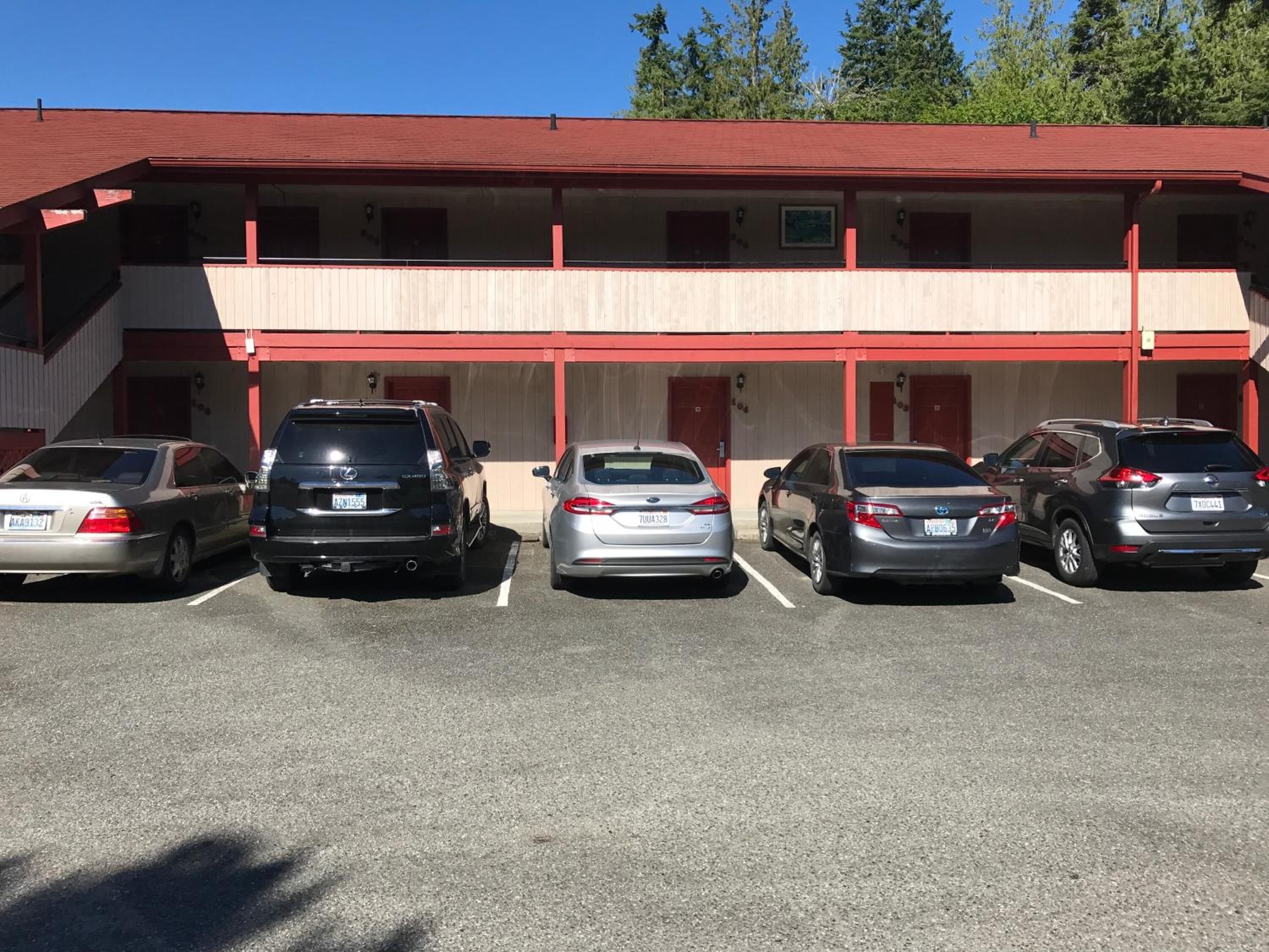 A motel with five parking spaces, each occupied by a car.