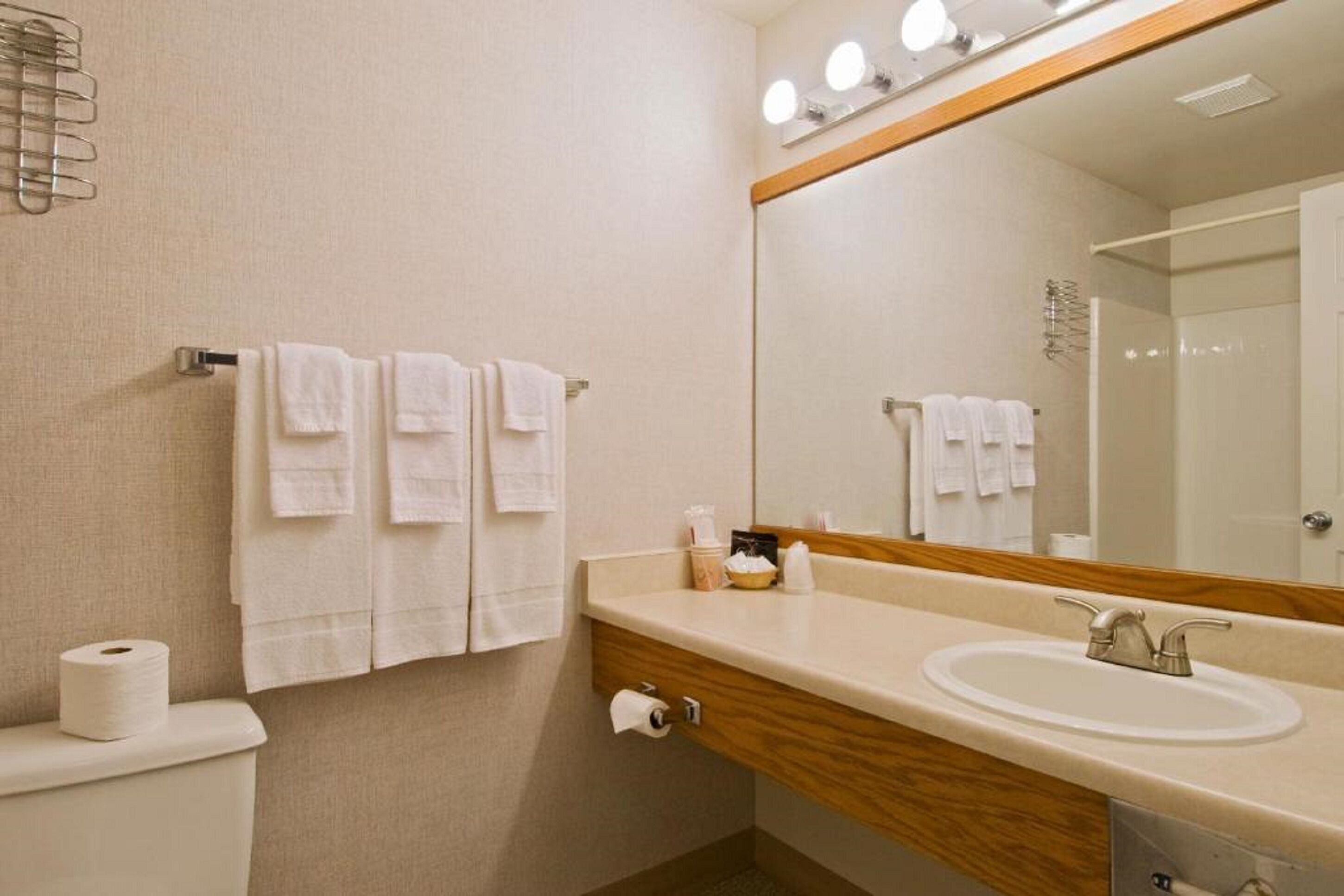 A bathroom with a sink, mirror, and towels.