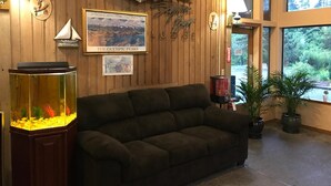 A cozy room with a wooden wall, a framed picture of The Olympic Peaks, a fish tank, and a couch. - Sequim Bay Lodge (Sequim)