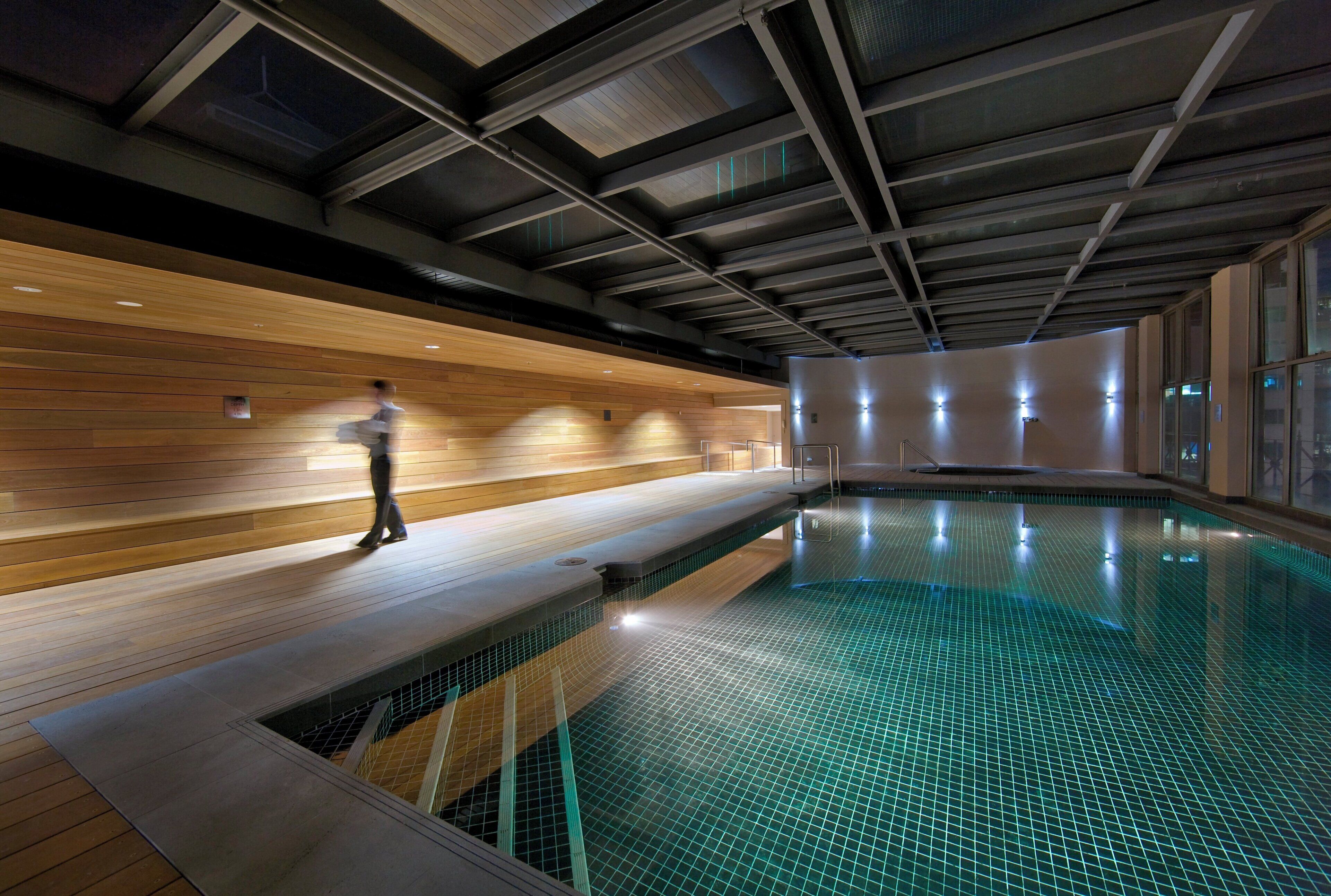 An indoor swimming pool with a wooden deck and a tiled floor.