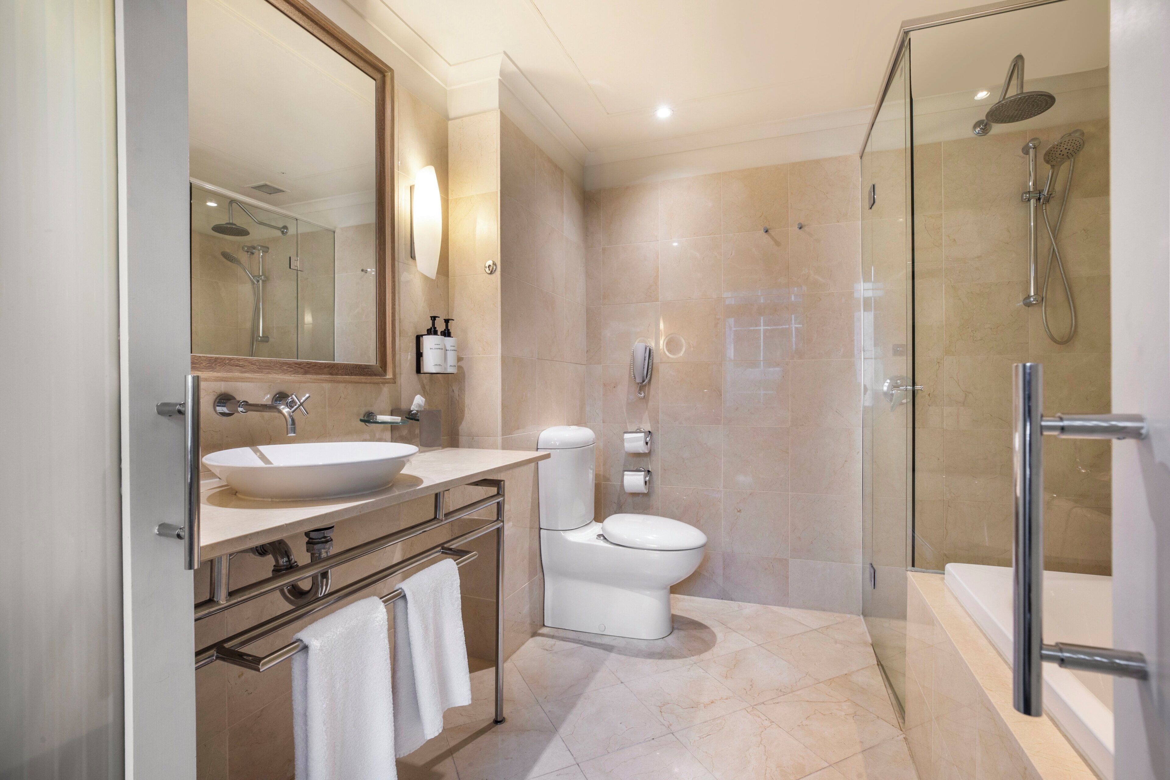 A modern bathroom with a large sink, toilet, and glass-enclosed shower area.
