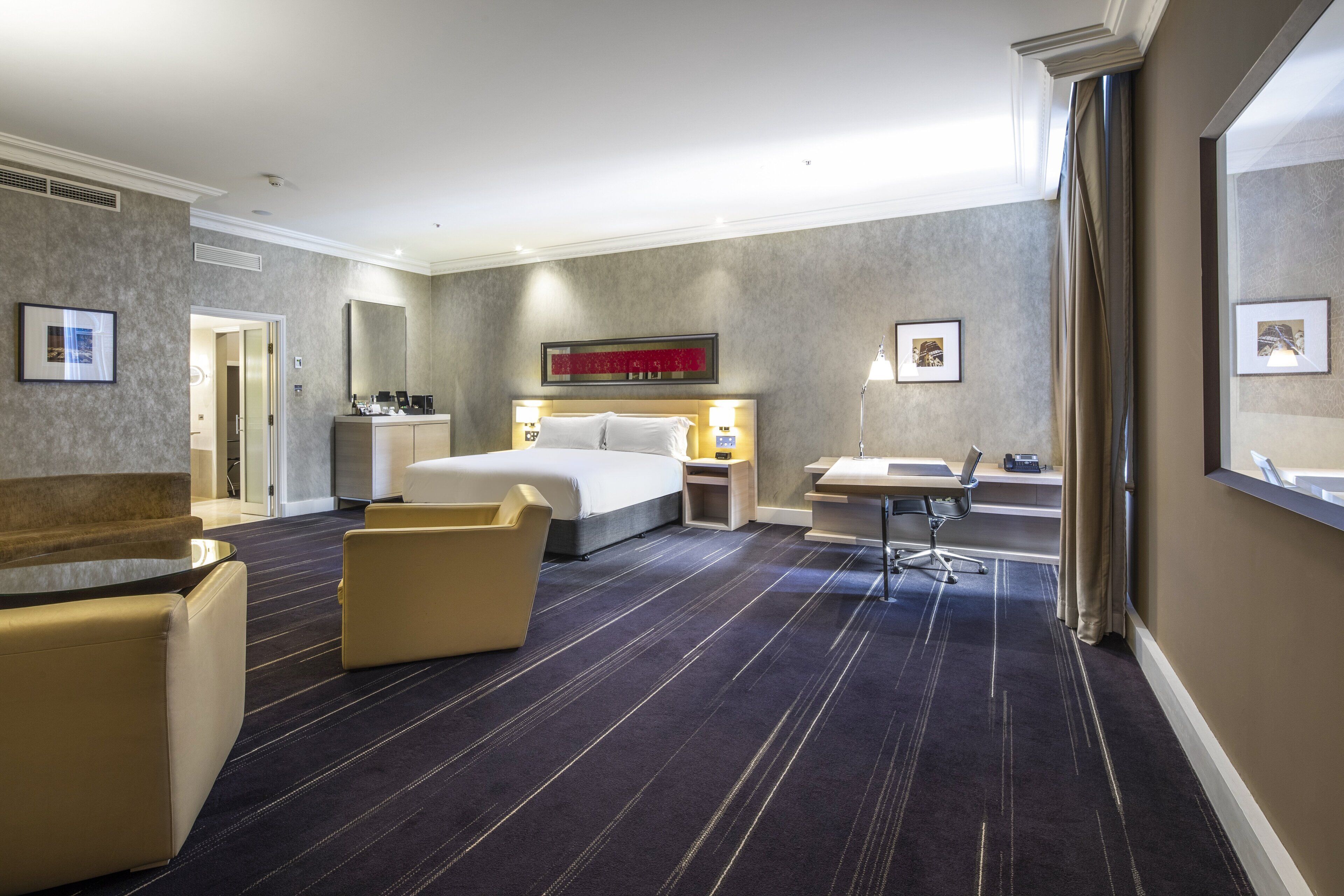 Ett hotellrum med en säng, ett skrivbord, en stol, en soffa och ett badrum.
