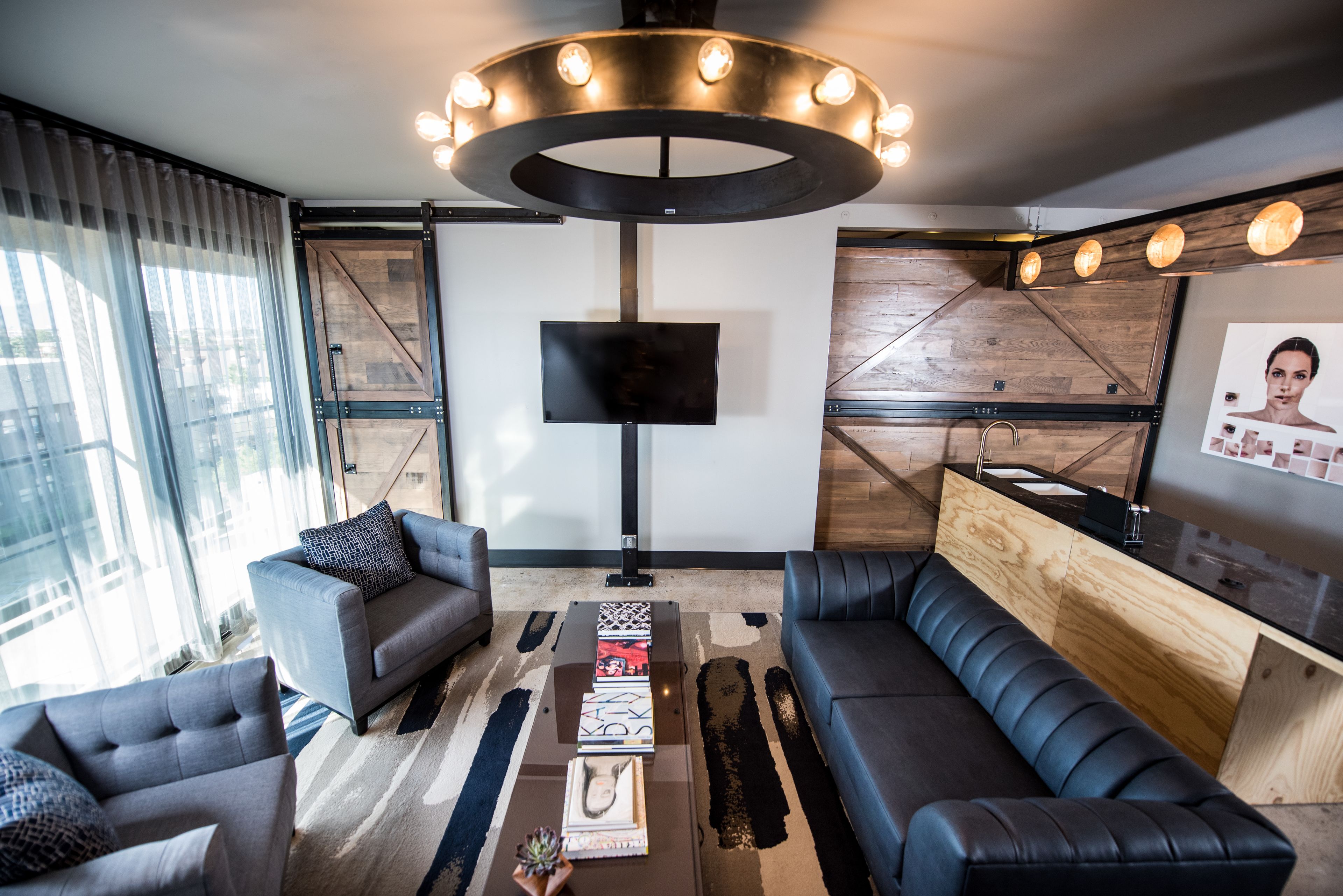 A modern living room with a large flat-screen TV, two sofas, a coffee table, and a wooden accent wall.