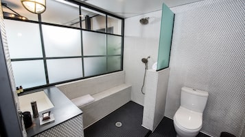 A modern bathroom with a large mirror, a toilet, and a shower area.