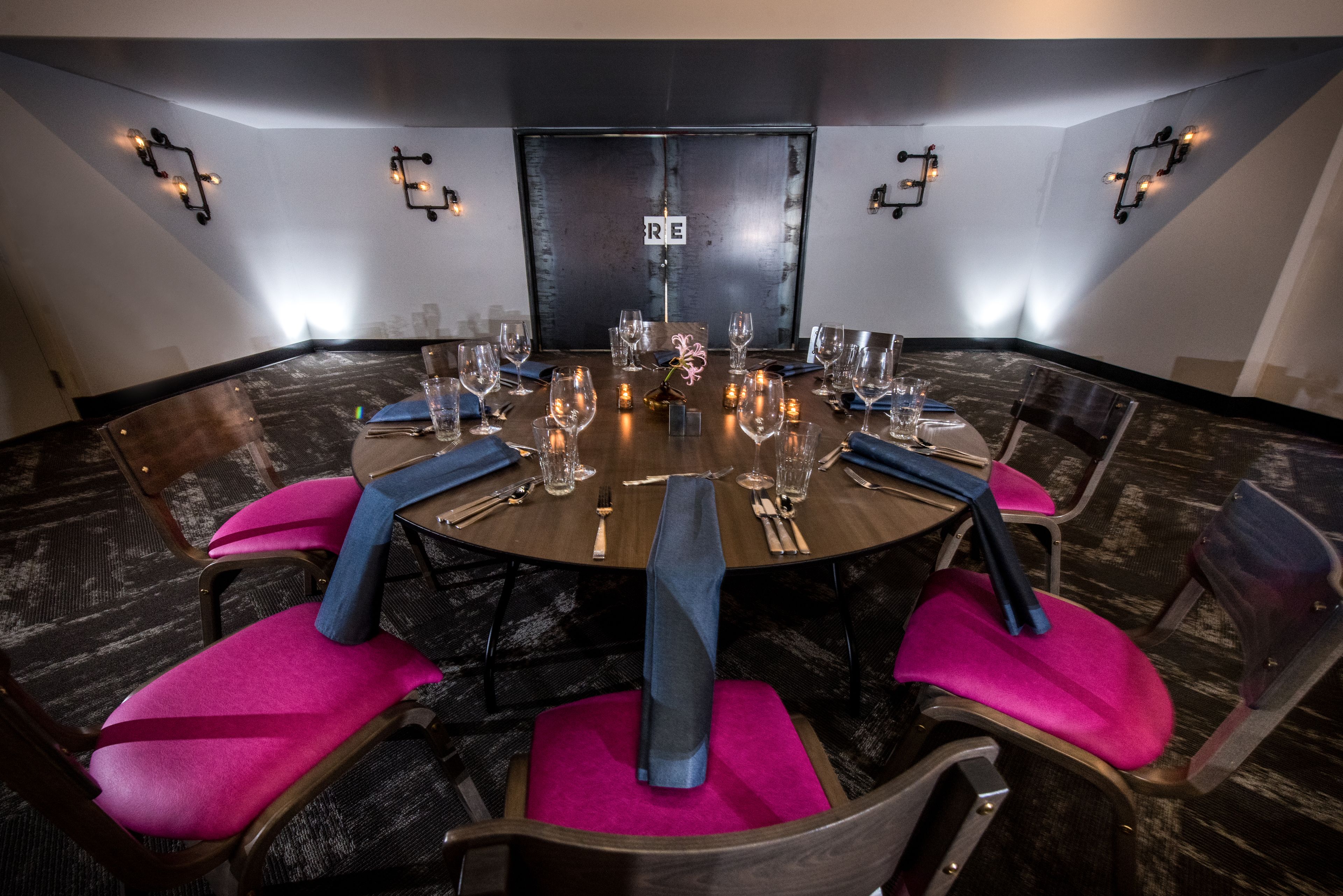 A conference room with a round table set for a meeting, equipped with chairs, tables, and glassware.