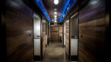 A hallway with wooden walls and a tiled floor, leading to a door at the end.