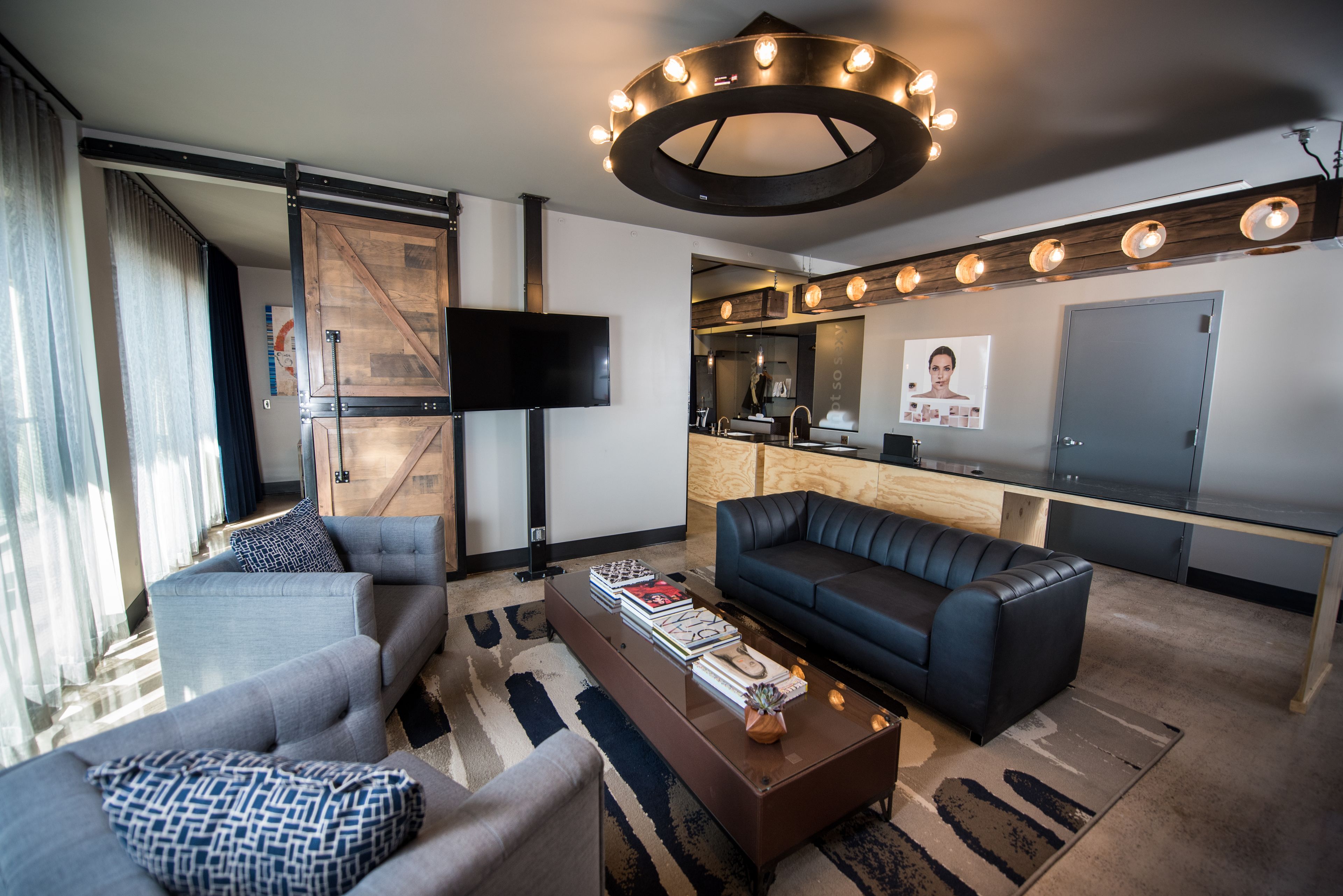 A modern living room with a sofa, armchairs, a coffee table, and a TV.