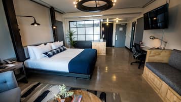 A modern hotel room with a large bed, a desk, a TV, and a sofa.