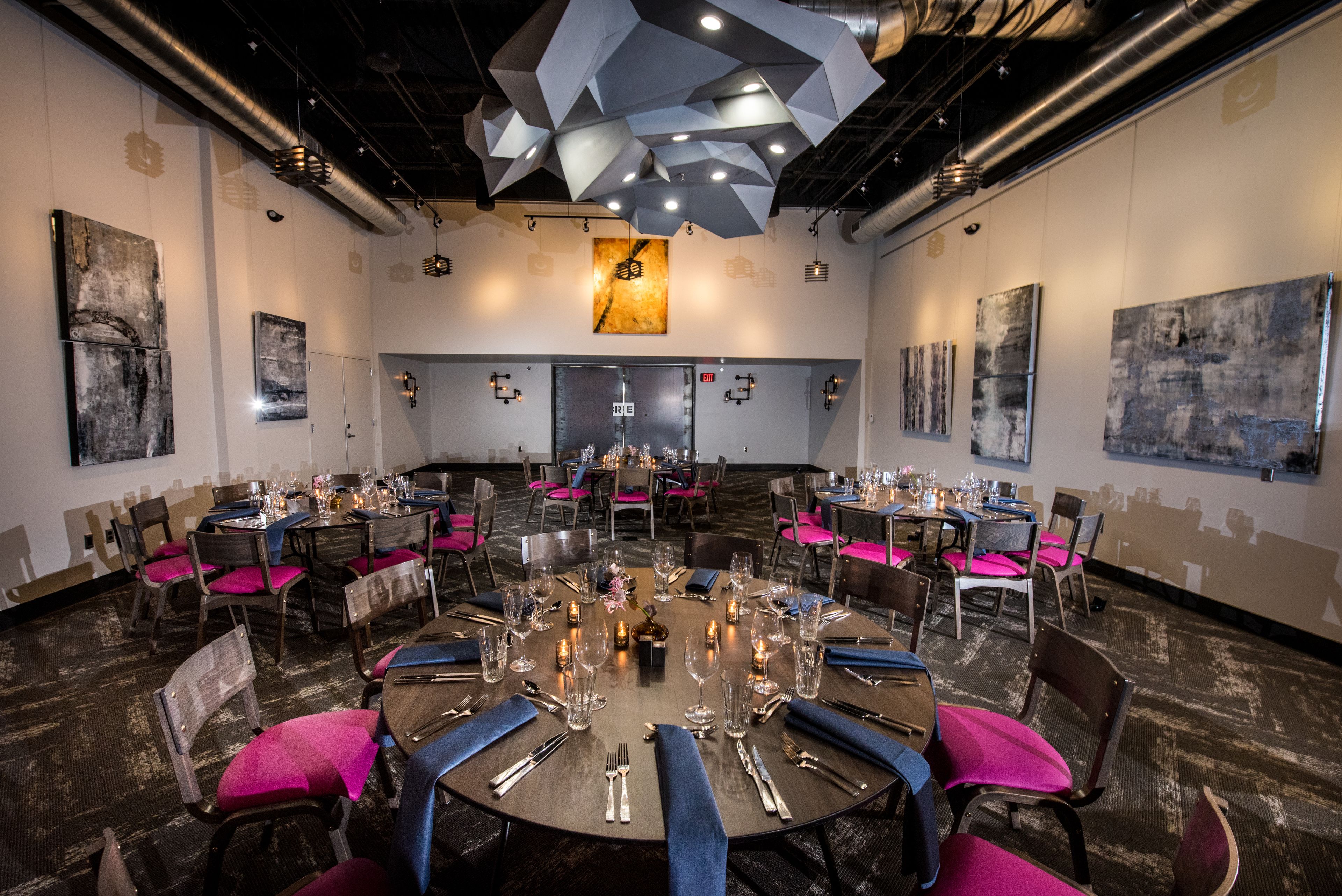 A conference room with round tables, chairs, and a central chandelier.