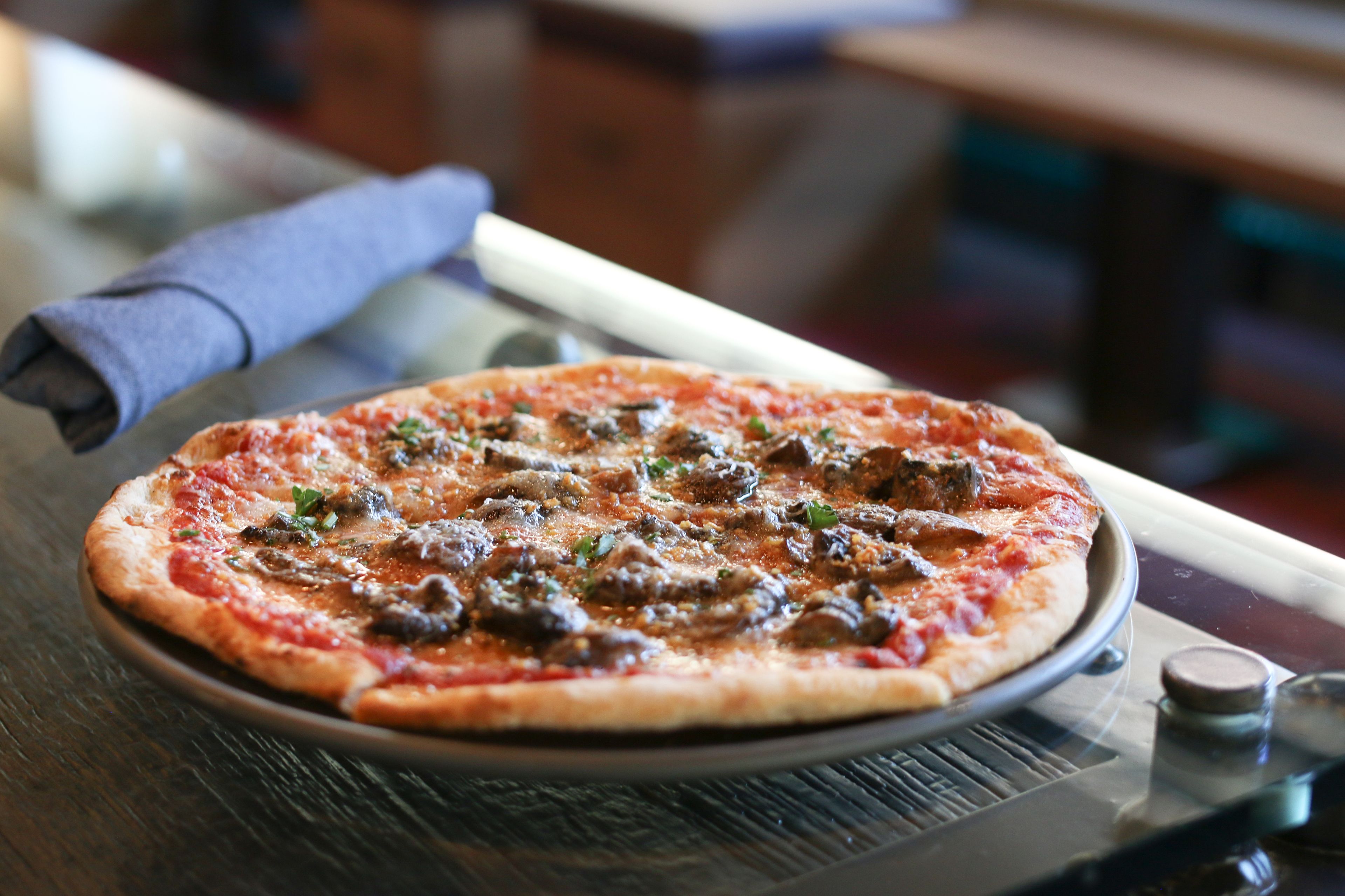 A pizza on a plate with a napkin beside it.