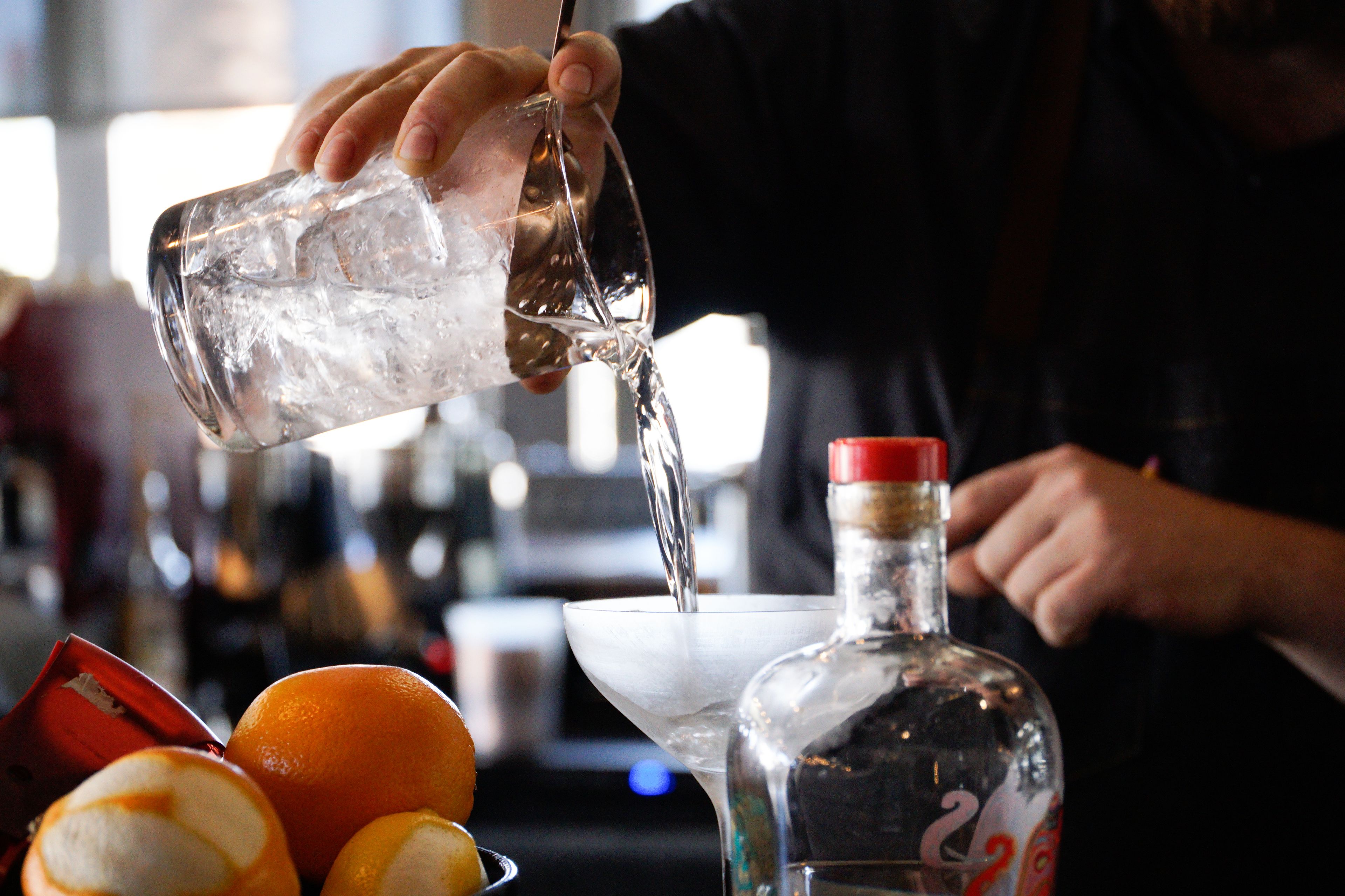 Un barman verse une boisson dans un verre à martini.