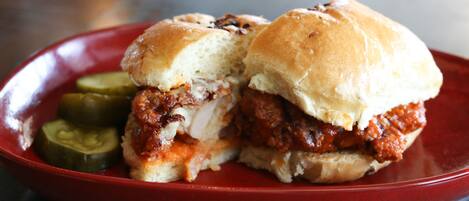 Un sándwich con pepinillos sobre un plato rojo.