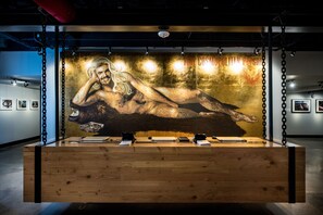 A wooden display table with a large painting of a muscular figure, surrounded by chains and spotlights.
