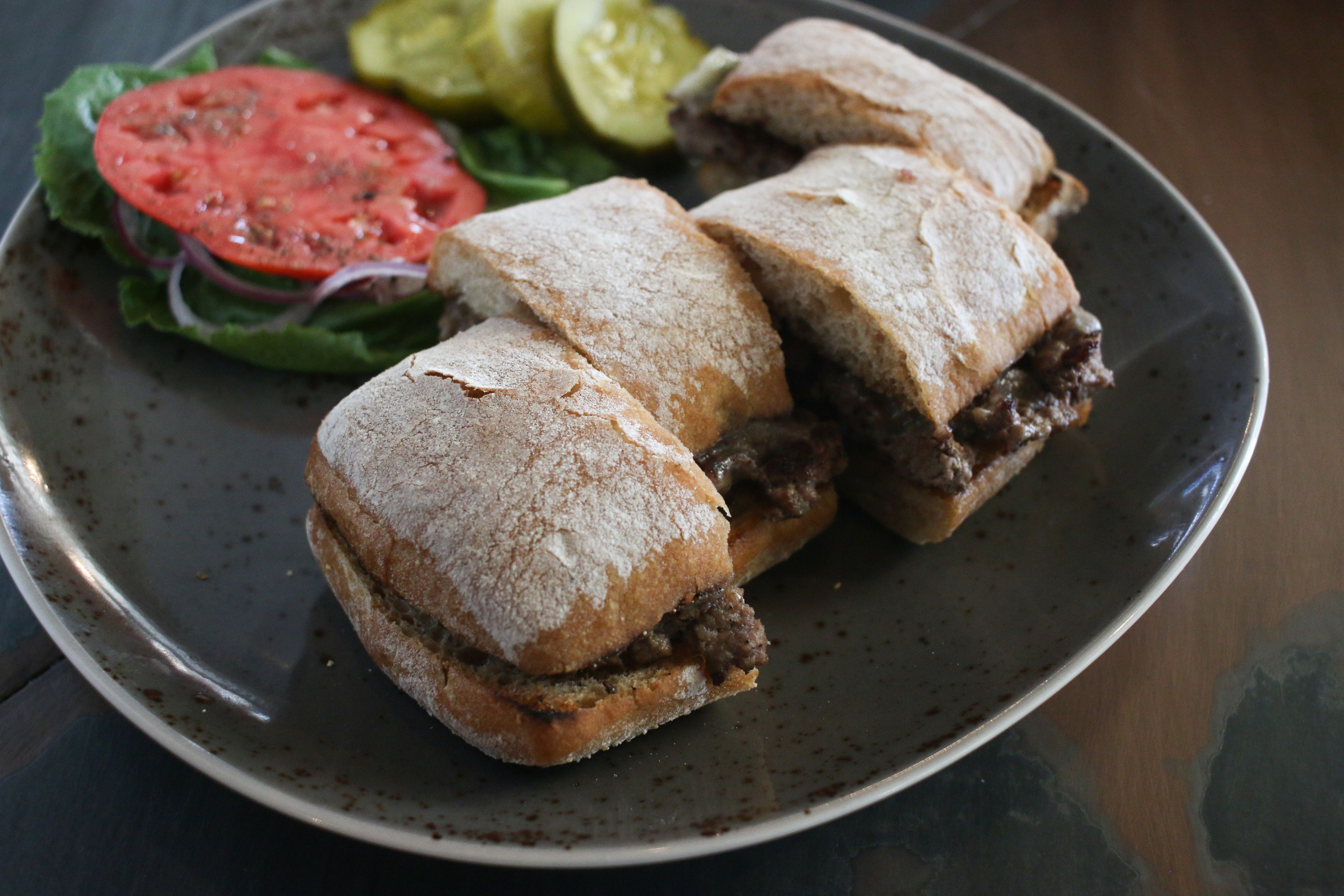 Un sandwich garni de viande et de légumes, servi sur une assiette.