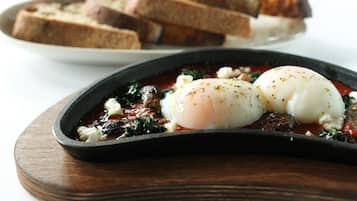 Un plat composé d’œufs pochés, d’épinards et de fromage feta, servi sur une planche en bois.