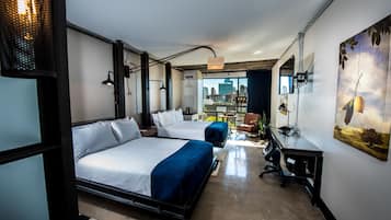 A modern hotel room with two beds, a desk, and a large window offering a city view.