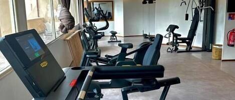 A modern gym with cardio equipment, a treadmill, and exercise bikes.