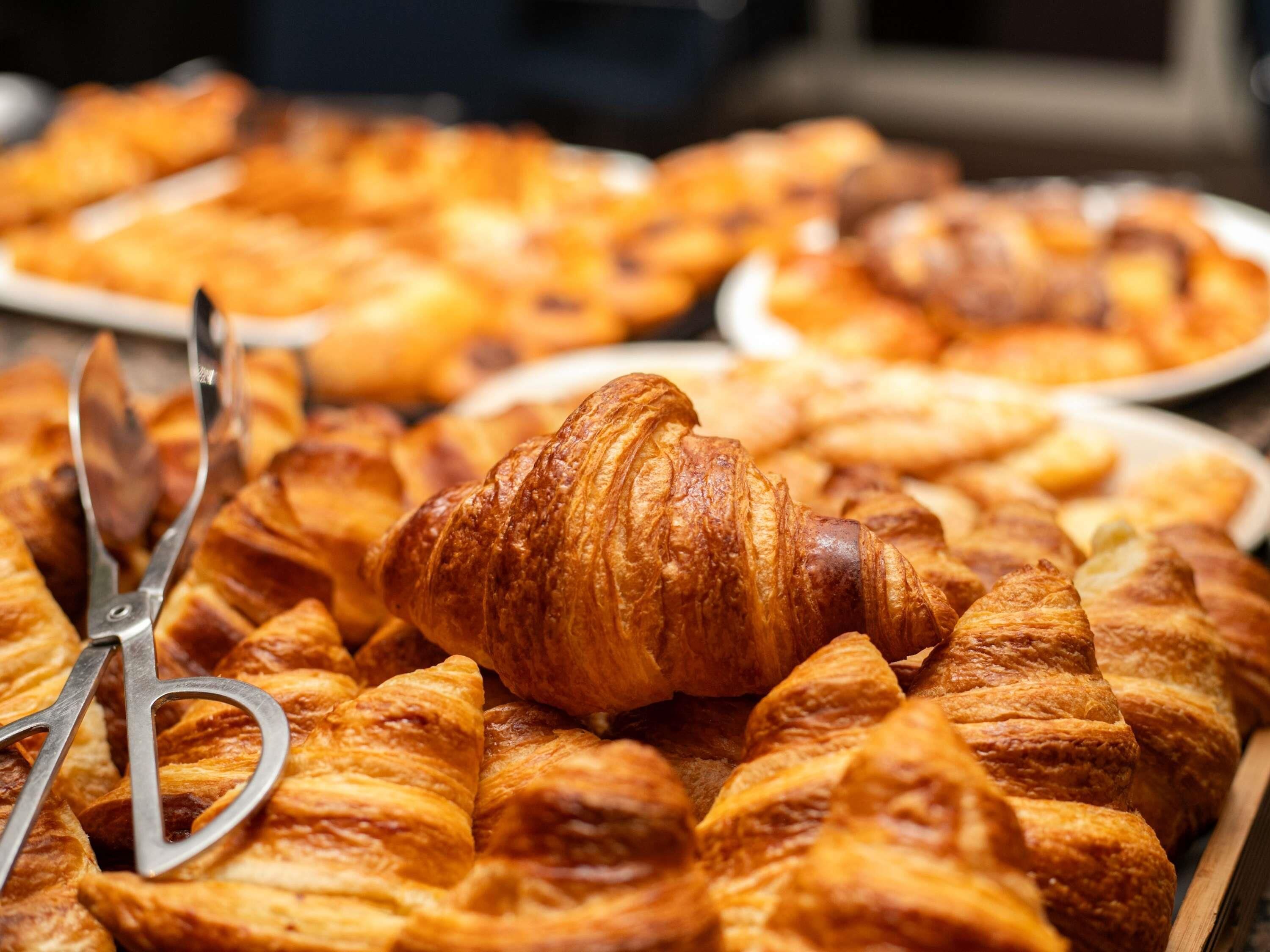 Variedad de pasteles, entre ellos croissants, dispuestas en platos.