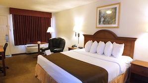 A hotel room with a large bed, a desk, a chair, a lamp, and a painting on the wall. - Days Inn by Wyndham Abilene (Abilene)