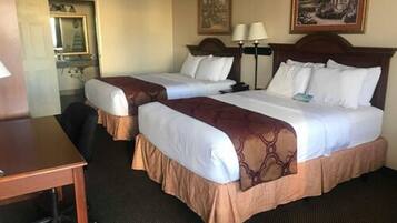 Une chambre d’hôtel avec deux lits, un bureau, une chaise et un miroir.