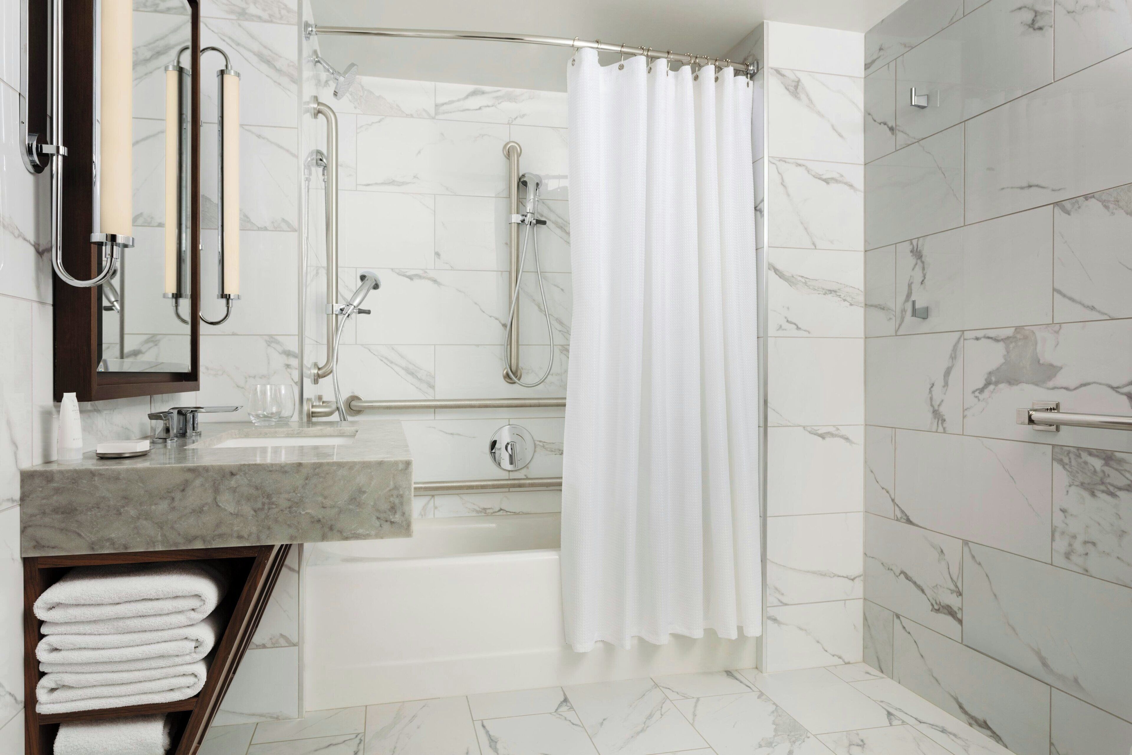 A modern bathroom with a bathtub, shower, and vanity.