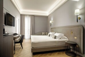 Ein Hotelzimmer mit Bett, Schreibtisch, Stuhl, Lampe und einem an der Wand hängenden Kunstwerk.