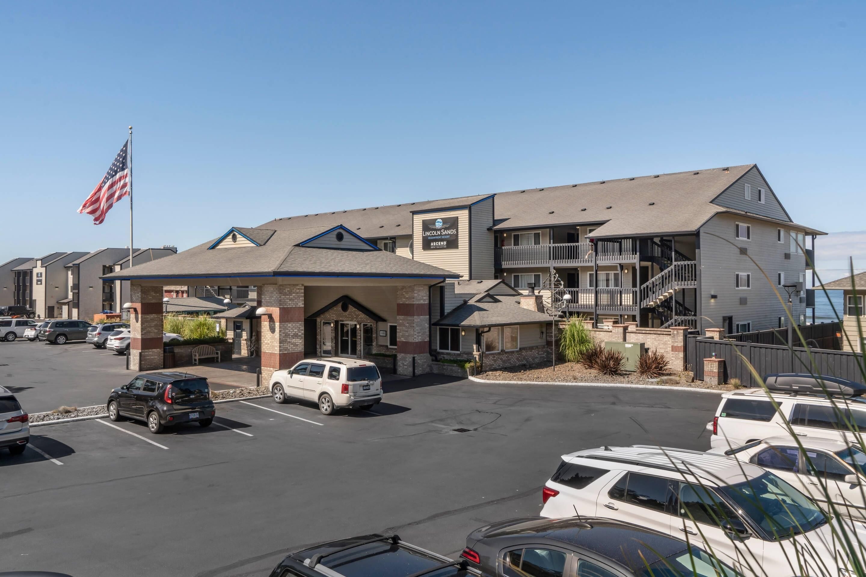 A hotel with a covered entrance, multiple floors, and a parking lot.