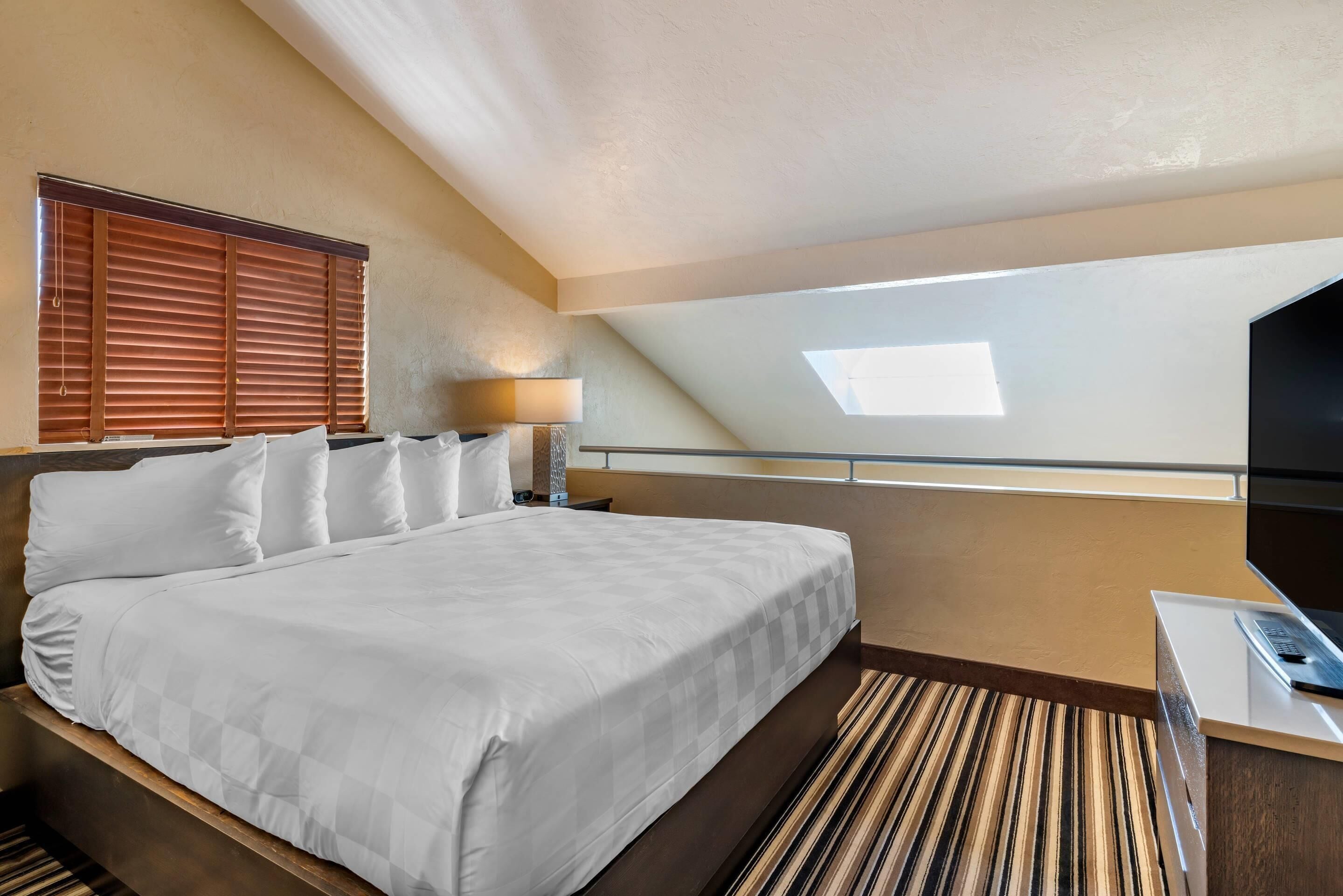 Una habitación de hotel con una cama grande, un escritorio, una lámpara y un televisor.