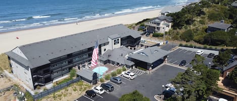 A hotel with a large parking lot, a pool, and a view of the beach.