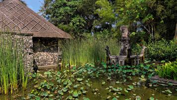 A pond with lily pads and a stone structure with a thatched roof.