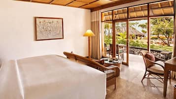 Quarto de hotel com uma cama grande, uma escrivaninha, uma cadeira e vista para o jardim pela janela.