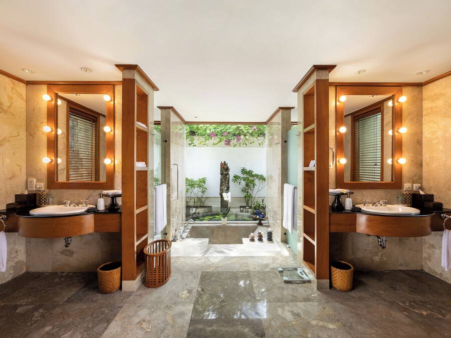 A luxurious bathroom with two sinks, large mirrors, and a central seating area with a small fountain.
