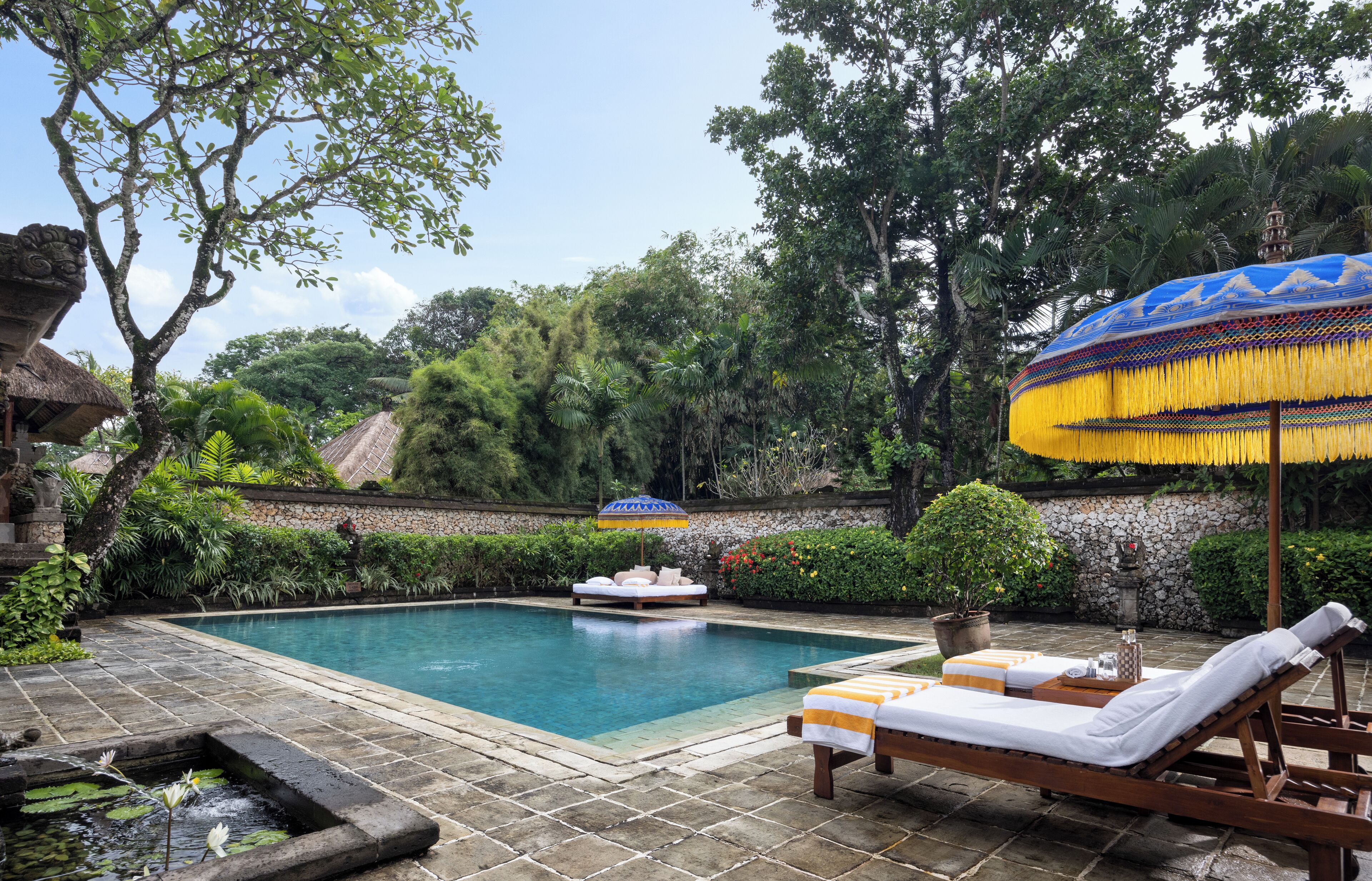 A pool area with a lounge chair, a small boat, and a decorative umbrella.