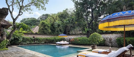 A pool area with a lounge chair, a small boat, and a decorative umbrella.