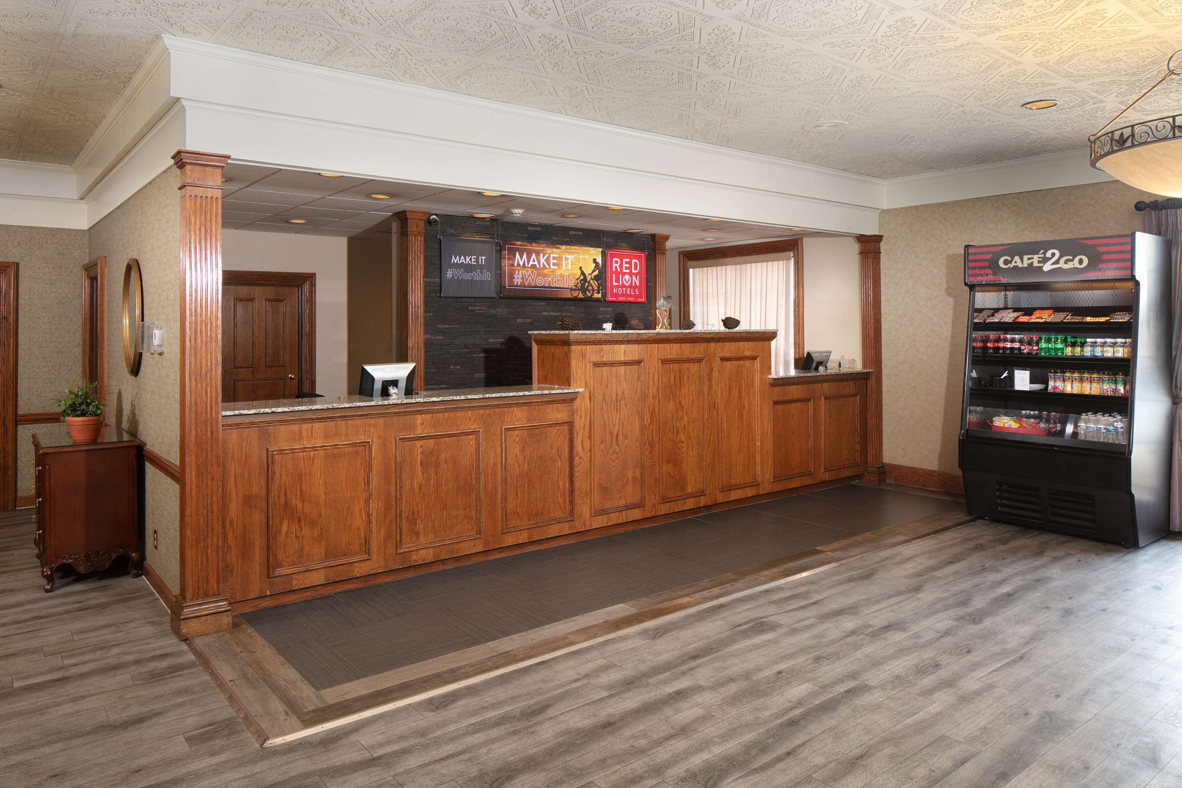 A reception area with a wooden reception desk, a digital display board, and a vending machine.