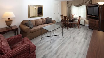 Una sala de estar con sofá, una mesa de centro de vidrio, televisor y un comedor con sillas y mesa.