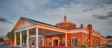 A hotel with a covered outdoor area, a brick facade, and a bell tower.