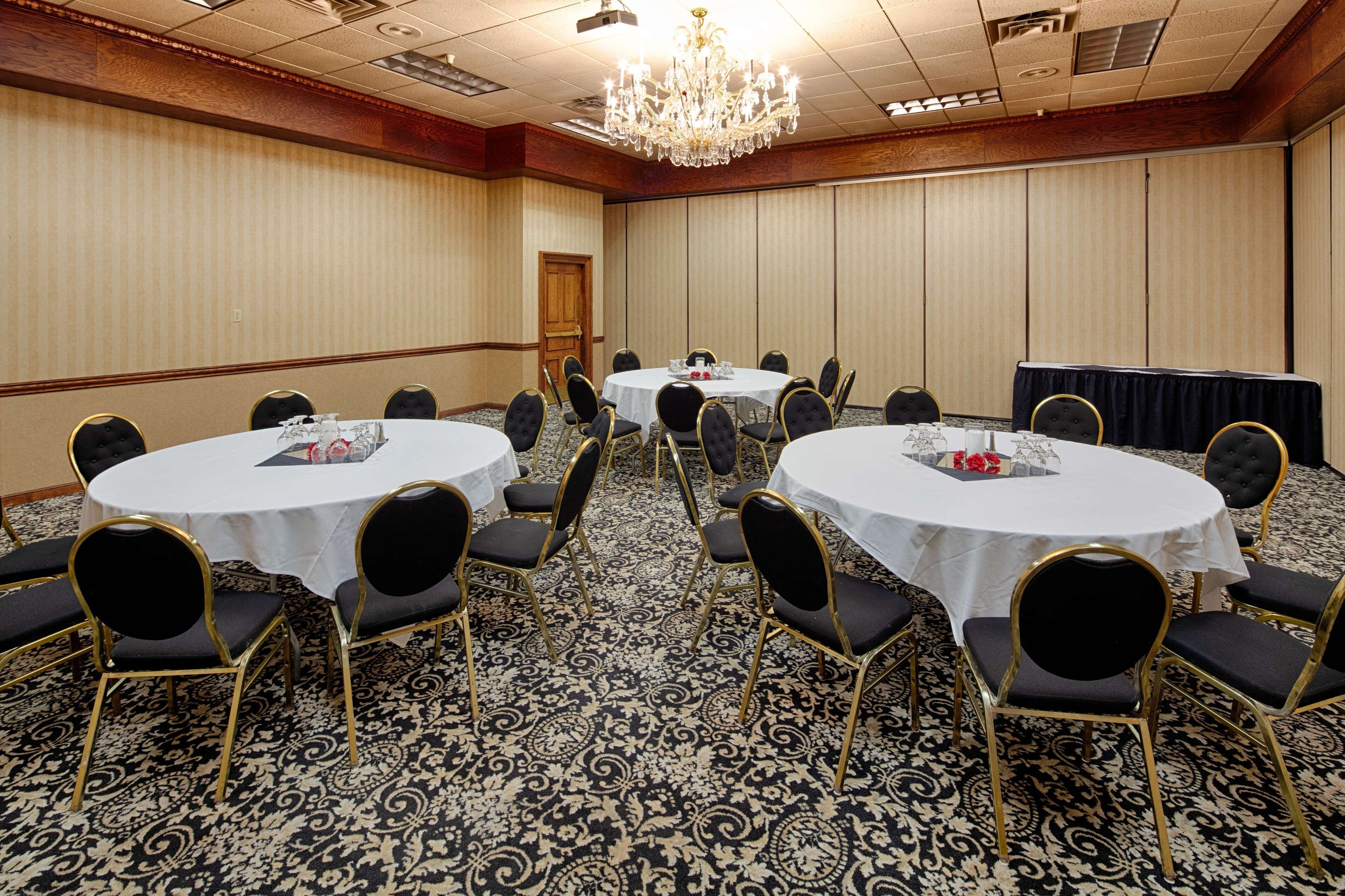 A conference room with round tables, black chairs, and a patterned carpet.
