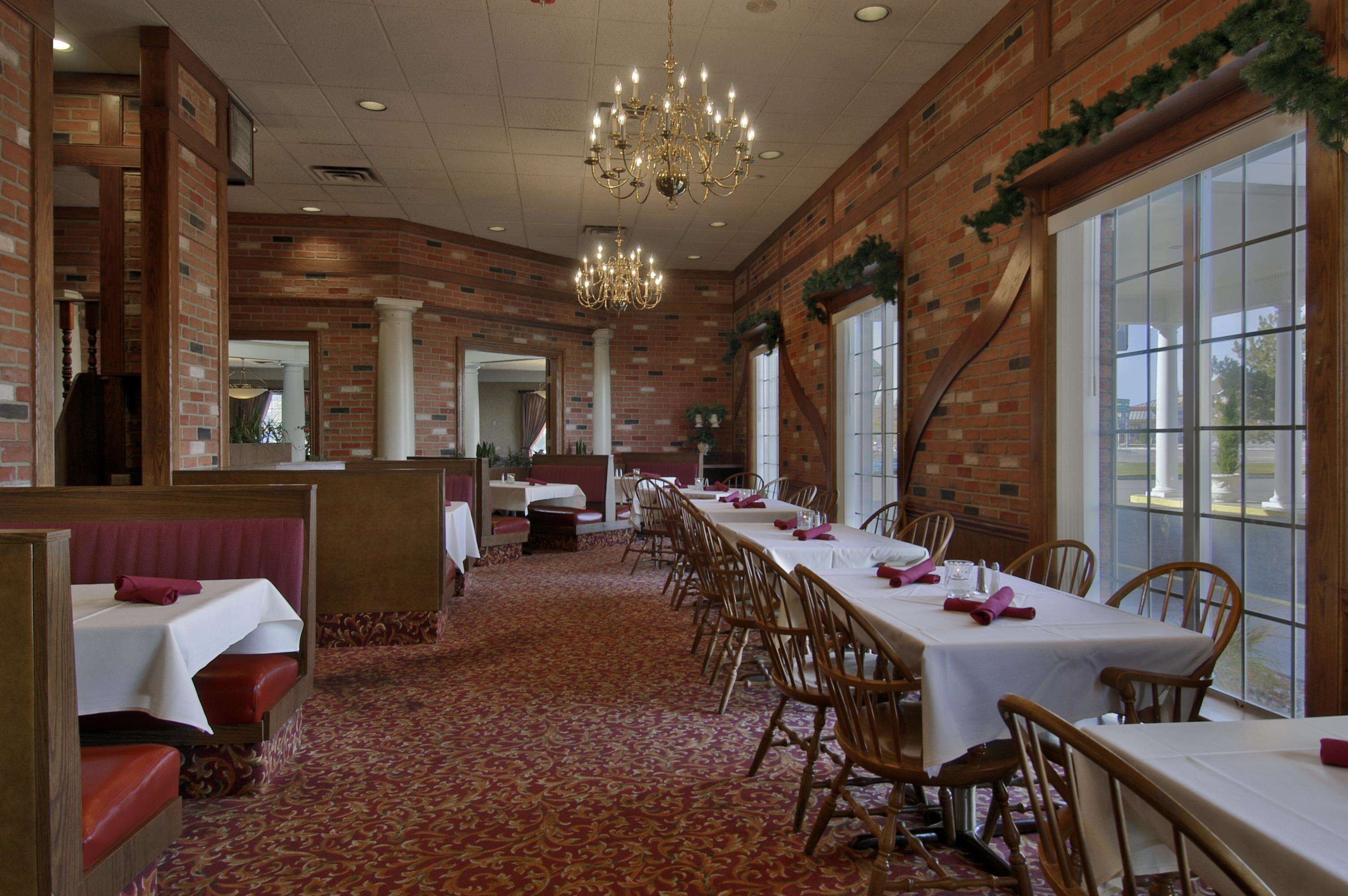 Une salle de banquet avec de longues tables, des chaises en bois et un lustre.